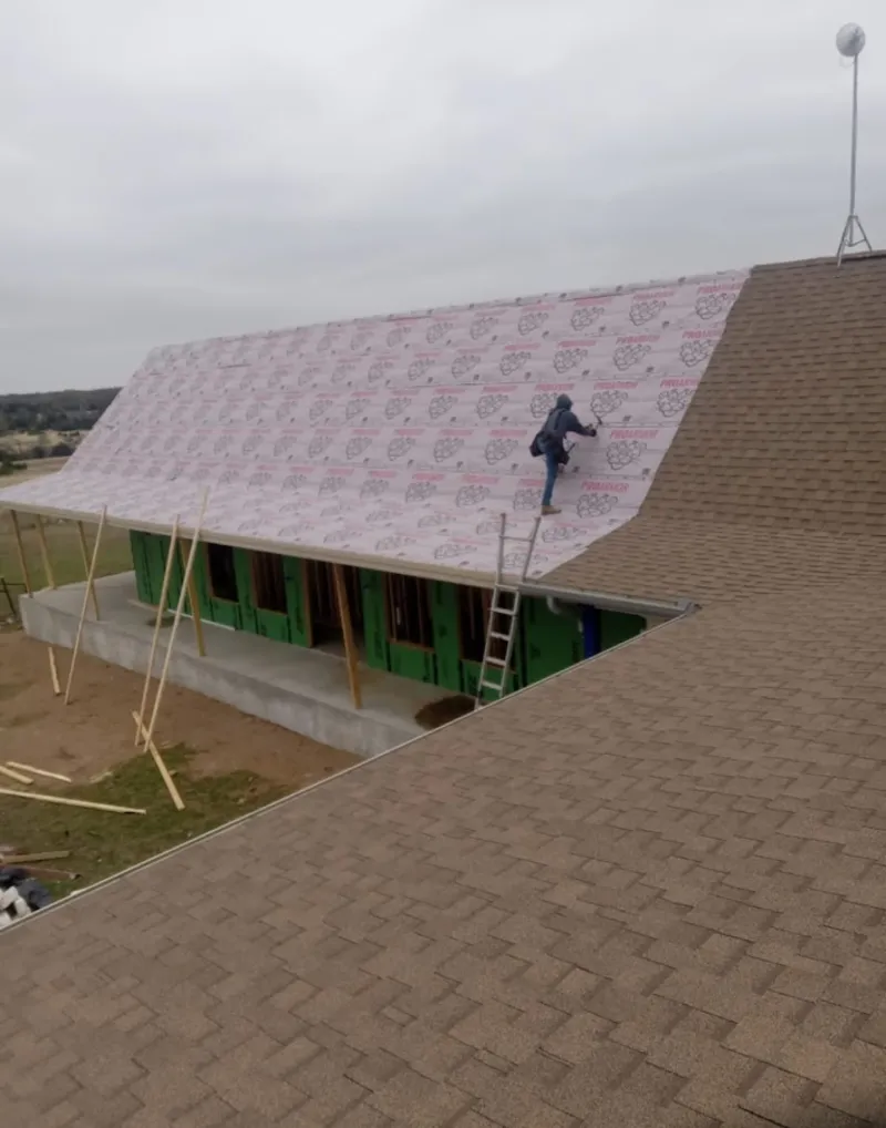 Worker preparing underlayment for a metal roof installation in Bossier City